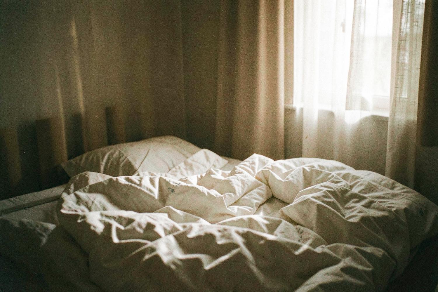 Morning light across an unmade bed